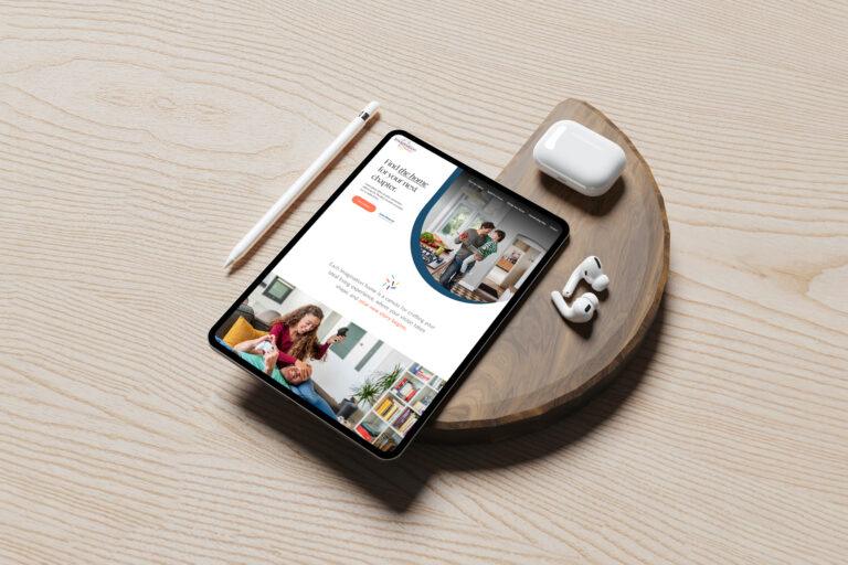 A tablet with a stylus displays a telemedicine service website, resting on a wooden tray beside wireless earbuds and a charging case—all placed on a light wood surface reminiscent of David Weekley Homes' signature style.